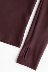 Campera deportiva corta color bordó con tecnología SoftMove y DryMove, de corte ajustado, cuello alto, cierre frontal y mangas largas con abertura para el pulgar.