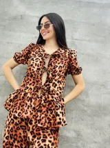 Blusa estampada con hojas verdes y blancas, con escote en V y mangas cortas abullonadas. Presenta volados en el ruedo y detalle de lazos en el frente.