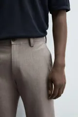 Pantalón chino de corte slim fit, confeccionado en tejido elástico. Presenta bolsillos frontales, bolsillos traseros de vivo con botón y cierre frontal con cremallera y botón.