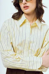 Camisa de manga larga con diseño a rayas verticales en tonos celestes y amarillos sobre fondo blanco, cuello camisero clásico y cierre frontal de botones.