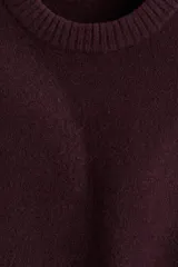 Buzo de tejido de punto color borgoña oscuro, con cuello redondo y acabado cepillado. Presenta remates acanalados en cuello, puños y bajo.