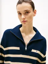 Sweater de punto con cuello alto y cierre de cremallera metálica, diseño de rayas horizontales en azul marino y beige, logo de Tommy Hilfiger bordado en el pecho. Confeccionado en algodón.