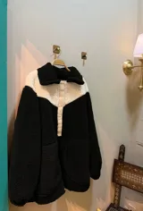 Buzo de corderito negro y blanco con cuello solapa y cierre parcial con botones.