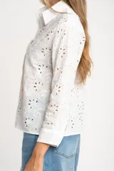Blusa blanca de manga larga con cuello camisero y bordado tipo broderie anglaise con diseño floral calado.