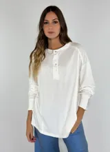 Remera blanca de manga larga con cuello redondo y botones.