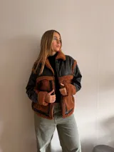 Campera negra de cuero sintético con cuello, solapas, puños y bolsillos de corderito color marrón.