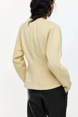 Buzo entallado de felpa color beige, con cuello redondo y mangas raglán largas, que presenta costuras moldeadoras en la cintura.