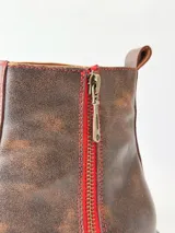 Botas cortas de cuero color chocolate, con elástico lateral, cierre interno con cremallera roja, pespuntes rojos y suela track.