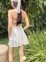 Vestido corto de tela satinada color plata, con diseño tipo corset en el top, breteles finos y falda con volados superpuestos.