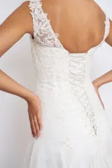 Vestido de novia blanco de seda y organza con apliques de cruni, bordados en perlas y canutillos. Sin mangas, con breteles transparentes y espalda terminada en V con cinta para cerrar tipo corset.