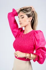 Top fucsia de algodón con elástico en el tronco y puños, mangas largas abullonadas y cuello redondo.