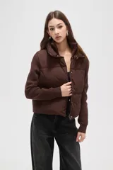 Campera híbrida con cuerpo delantero acolchado tipo puffer y mangas de tejido de punto acanalado con cuello alto. Presenta un diseño corto y holgado con cierre frontal oculto.
