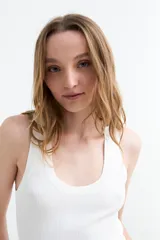 Top tejido en canalé color blanco, de corte ajustado, sin mangas y con escote redondo pronunciado.