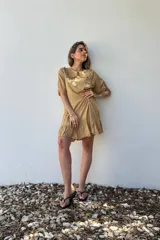 Vestido corto color beige de voile de rayon, con cuello bebé con volados y mangas cortas abullonadas.