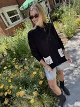 Cárdigan negro de punto con cierre frontal de cremallera, bolsillos de parche con diseño bordado y mangas largas. Tejido de algodón y acrílico.