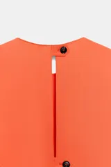 Vestido midi color naranja de la colección ZW de Zara, con cuello redondo, manga corta y detalle de tejido drapeado con volados en el delantero. Cuenta con cierre en la espalda con abertura y botón.