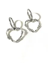 Par de aros colgantes plateados con forma de corazón hecho de alambre de púas y cierre de aro pasante.