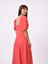 Vestido midi color salmón, con escote cuadrado, mangas cortas abullonadas y detalle de abertura en el pecho.