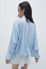 Camisa de manga larga con estampado de rayas verticales, cuello clásico y botonadura frontal. Incluye una corbata extraíble a juego con tira elástica. Presenta puños con abertura y botón, canesú con pliegue en la espalda y bajo recto con aberturas laterales redondeadas.