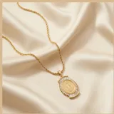 Cadena de eslabones tipo cuerda con dije de medalla milagrosa enmarcado por circonias brillantes y detalles en forma de abanico.