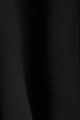 Campera negra de tejido efecto neopreno, con cuello chimenea alto, cierre frontal metálico y bajo fruncido con elástico. Presenta hombros caídos y corte corto.