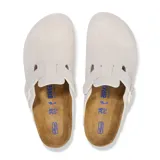 Zueco tipo mule de gamuza en color blanco, con diseño de punta cerrada, tira ajustable con hebilla lateral y plantilla anatómica de corcho.