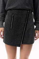Minifalda negra con aplicación de strass plateados y cierre con cremalleras metálicas diagonales.