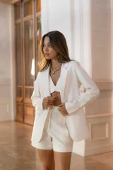 Blazer color blanco con solapas de muesca, corte clásico y bolsillos delanteros.