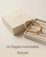 Pulsera tipo esclava rígida de acero con baño de oro, con diseño grabado en la superficie.