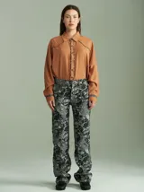 Camisa negra de algodón con mangas largas, cuello camisero y detalles de ribetes estampados a cuadros en los hombros, puños y aberturas de botones.