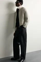 Pantalón relaxed fit negro confeccionado en tejido de algodón con estructura diagonal, estilo de cinco bolsillos y cierre frontal con cremallera y botón metálico.