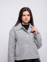 Tapado gris de corte recto con cuello solapa y cierre frontal con tres botones a tono. Tiene bolsillos laterales tipo parche.