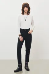 Jean de corte mom en color negro, con diseño de tiro alto, cinco bolsillos y detalle de rotura en la rodilla izquierda.