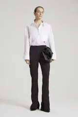 Pantalón de tiro alto con estampado abstracto en tonos borgoña y negro, con cierres invisibles en la parte inferior de la bota en los laterales y recortes verticales.