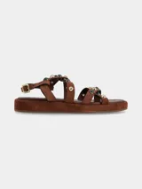 Sandalias planas de cuero gamuza color marrón chocolate, con tiras cruzadas decoradas con apliques metálicos y piedras. Cierre ajustable con hebilla en el tobillo y suela forrada.