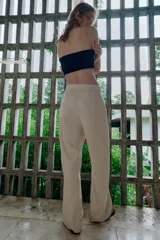 Pantalón de tiro medio confeccionado en lino color beige, de pernera recta con nervios marcados en el delantero. Posee bolsillos frontales, falsos bolsillos de vivo en la espalda y cierre frontal con cremallera, botón interior y gancho.