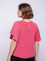 Top rosado de mangas cortas con volados, cuello redondo y detalle diagonal en el frente.