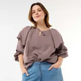 Blusa fluida de manga larga con diseño a rayas en tonos marrón y blanco, con escote redondo adornado con una pequeña abertura y tiras para anudar, y un gran volante superpuesto en los hombros.