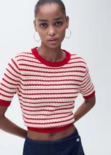 Jersey de punto crochet con diseño de rayas horizontales en color rojo y crema. Presenta cuello redondo, mangas cortas y terminaciones en rib acanalado de color rojo sólido.