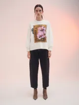 Buzo blanco de corte clásico con estampa rectangular centrada en el frente con flores rosadas y texto en color ocre.