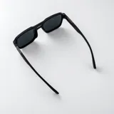 Lentes de sol polarizados con armazón gris translúcido de diseño cuadrado y doble puente, con cristales oscuros.