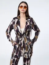 Chaqueta sastrera con estampado abstracto en tonos marrón, beige, azul y negro. Presenta solapa delantera de satén, mangas largas con hombreras y lazo para ajustar en la cintura.