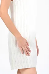 Vestido corto color blanco con hilos dorados, sin mangas y corte recto.