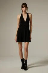 Vestido corto negro con escote halter profundo y corte ajustado al cuerpo.