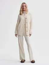 Cárdigan largo color crema, confeccionado en tejido de punto acanalado de viscosa. Tiene corte relajado, cierre frontal con botones y bolsillos de parche.