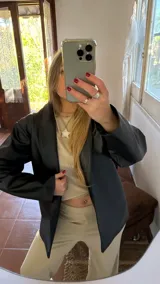 Blazer negro de cuero sintético con cuello solapa y corte estructurado.