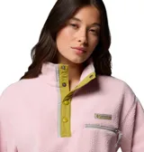 Polar Columbia modelo Helvetia II Cropped de color rosado, confeccionado en tejido suave de corderito. Cuenta con cuello alto con botones a presión en color verde oliva, bolsillo con cremallera en el pecho y mangas largas.