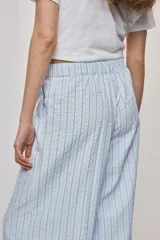 Pantalón de tiro alto con silueta amplia y caída fluida, confeccionado en tejido celeste con textura a rayas finas. Cuenta con cintura elástica con lazo de ajuste y bolsillos laterales.