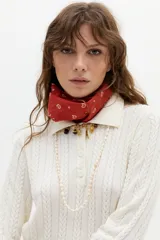 Sweater tipo polo color blanco roto, tejido en ochos, con cuello clásico y media cartera de botones.