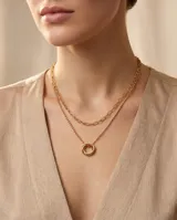 Collar doble de acero dorado compuesto por una cadena de eslabones alargados y una cadena de bolitas con un dije central de dos círculos entrelazados.